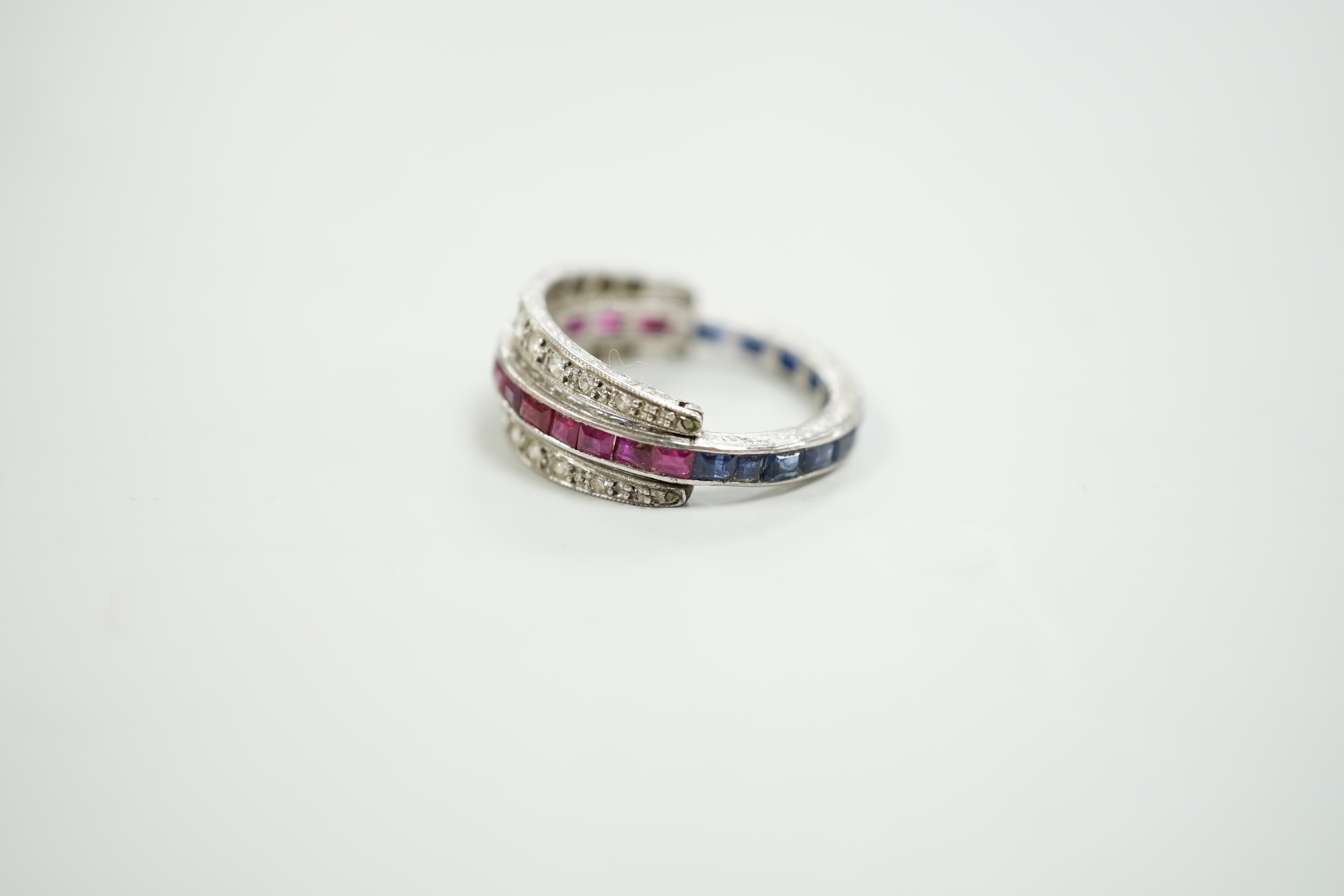 An early to mid 20th century platinum?, ruby, sapphire and diamond set swivelling triple band half eternity ring, size Q, gross weight 4.6 grams.